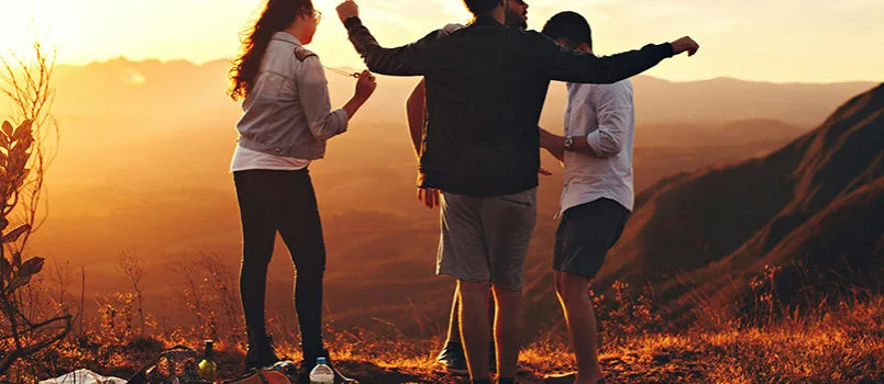 Grupo de amigos disfruta del atardecer durante un viaje en grupo.